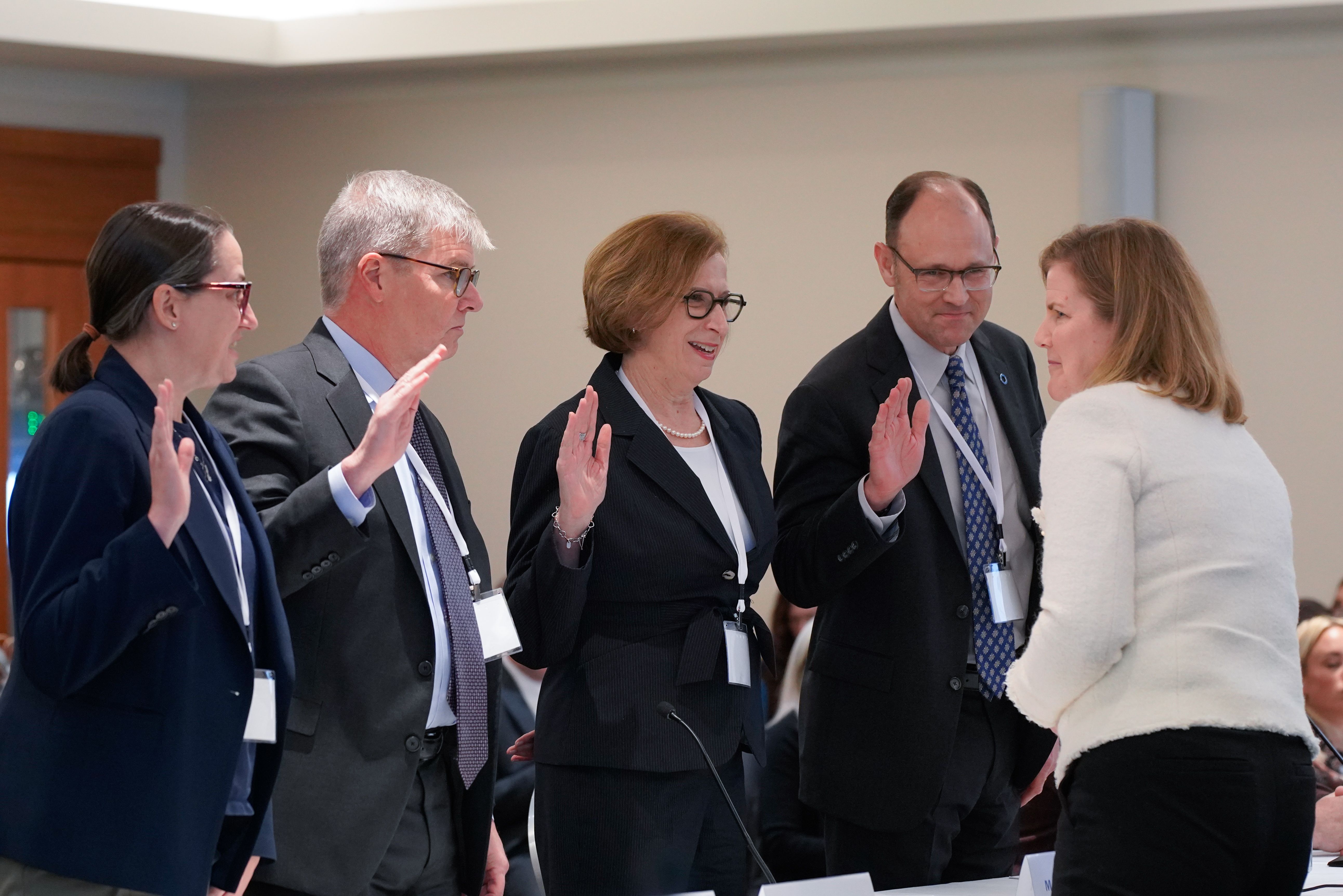 Photo of the four panelists on panel 4, each of the panelists are raising their right hand while being sworn in under oath by a member of HPC staff.